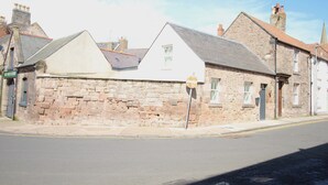 A stone building with a gabled roof, a visible window, and a door.