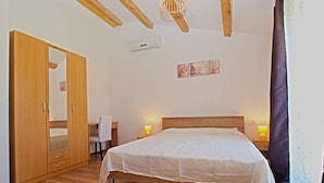 A bedroom with a wooden bed, a wardrobe, a desk, and a chair.