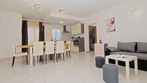 A modern living room with a sofa, a coffee table, and a dining area with chairs and a table.