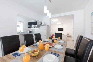 Un coin repas avec une table mise pour le petit-déjeuner, comprenant des assiettes, des verres et un panier de fruits.