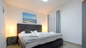 A bedroom with a bed, nightstands, a painting, and a view of the outdoors. - Holiday home with terrace for 2 people (Vantačići)