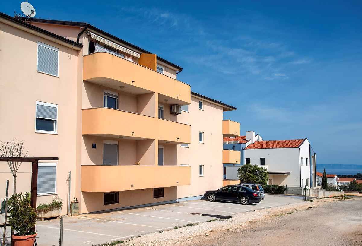 Un immeuble résidentiel à plusieurs étages, doté de balcons, d’un espace de stationnement et offrant une vue dégagée sur la mer.
