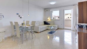 A modern living room with a dining area, a sofa, and a kitchen counter.