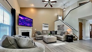 Una sala de estar moderna con un sofá modular, un reposapiés y un televisor de pantalla plana.