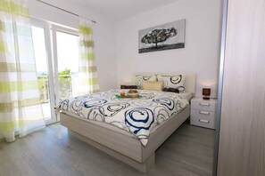 Una camera da letto con un letto, comodini, un tavolino di fianco al letto, una finestra con tende e un quadro appeso al muro.