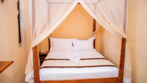 A bed with a canopy, white bedding, and a wooden headboard. - Island Stone Town Hotel (Zanzibar Town)