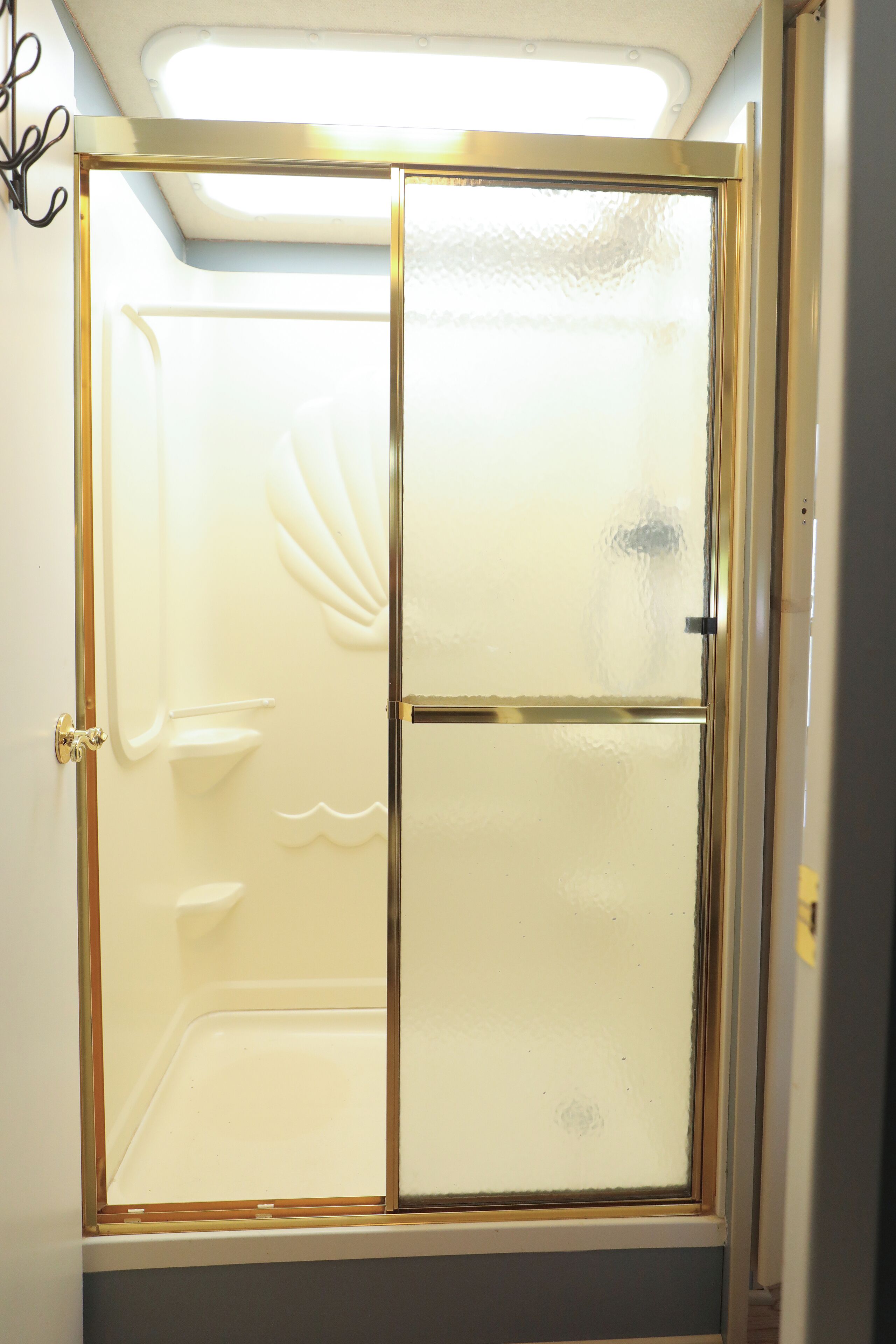 Un baño con cabina de ducha de vidrio, una bañera blanca y una puerta con pomo dorado.