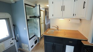 Una cocina compacta con refrigerador, lavamanos y armarios.