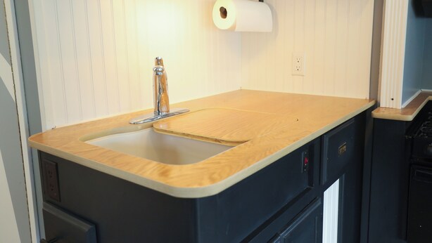 Una cocina con encimera de madera, un lavamanos y un rodillo de papel de cocina.