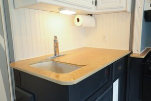 Une cuisine avec un plan de travail en bois, un évier et un rouleau d’essuie-tout.