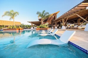 Zona de piscina amb gandules i una construcció amb teules.