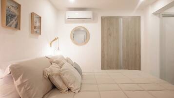 Un dormitorio con cama, armario, equipo de aire acondicionado y espejo en la pared.