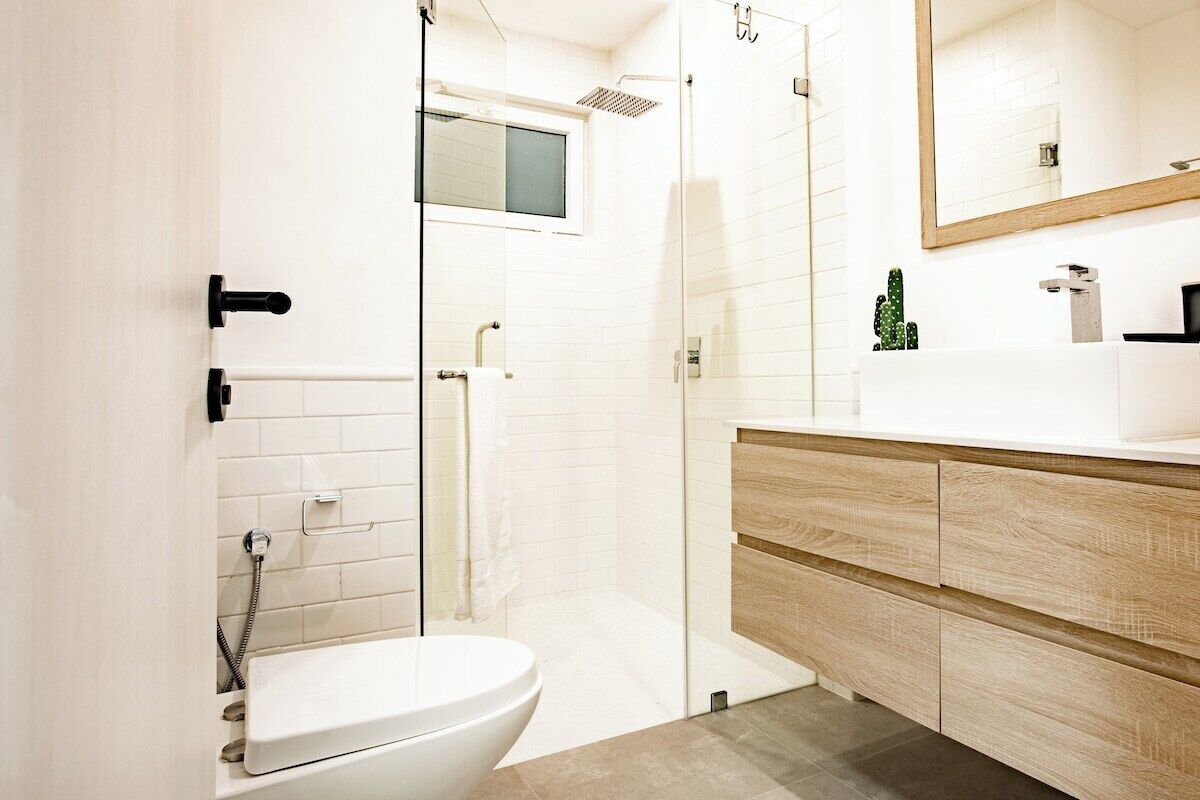 A modern bathroom with a toilet, shower, and vanity with drawers.