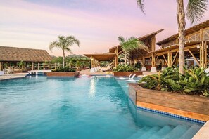 Un espace piscine avec des terrasses en bois et des palmiers.