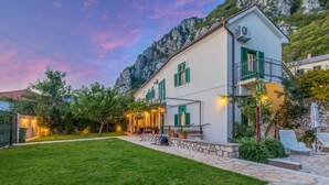 A two-story building with a stone pathway leading to a patio area with outdoor seating. - Villa with pool for 8 people (Grižane)