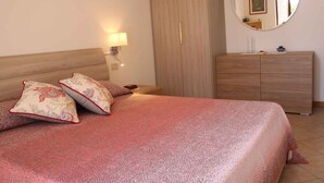 Un dormitorio con cama, almohadas, cómoda, espejo y mesita de noche.