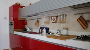 Una cocina moderna con gabinetes rojos, encimera blanca y varios electrodomésticos.
