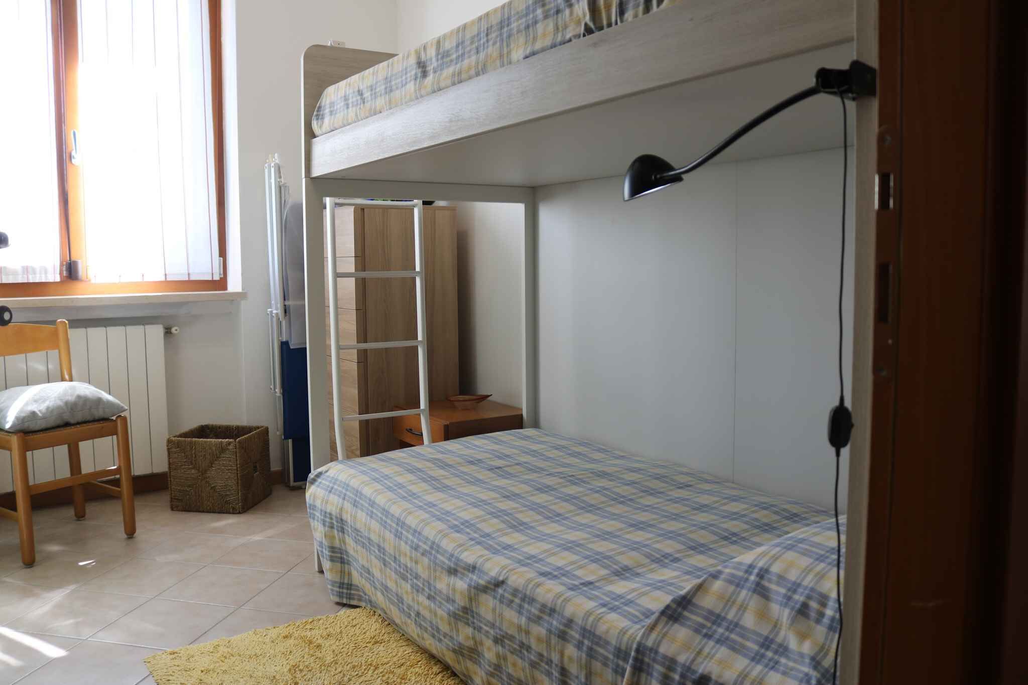 Een slaapkamer met een stapelbed, een bureau en een stoel.