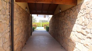 Un pasillo de paredes de piedra con suelo de baldosas que conduce a la entrada de un edificio.
