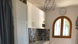 Eine Küche mit weißen Schränken, einer gefliesten Spritzschutzwand, einem Holztisch und einem Fenster mit Blick auf Bäume.