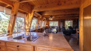 A cabin interior with a kitchen area featuring a double sink, wooden cabinets, and a dining table with chairs. - Enjoy a cozy cabin near the lake! Sleeps 8,  4 Beds. (Panguitch Lake)
