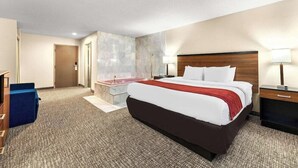 Une chambre d’hôtel avec un grand lit, un bureau, une coiffeuse avec un miroir et une salle de bain avec une baignoire.