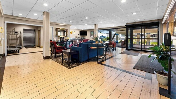 Un hall d’entrée spacieux avec un plancher en bois, un comptoir de réception, un espace salon et une vue sur l’extérieur.