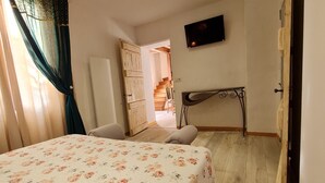 A bedroom with a bed, a desk, a TV, and a staircase leading to another room. - Chambre d'hôte Opale - Refinement, serenity and well-being guaranteed (Puy-l'Évêque)
