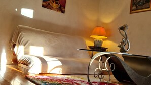 A cozy living room with a white sofa, a colorful rug, a table with a lamp, and a painting on the wall. - Chambre d'hôte Opale - Refinement, serenity and well-being guaranteed (Puy-l'Évêque)