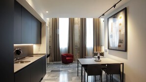 Una cucina moderna con piano cottura integrato, un'area pranzo con tavolo e sedie, e una sedia rossa nell'angolo.