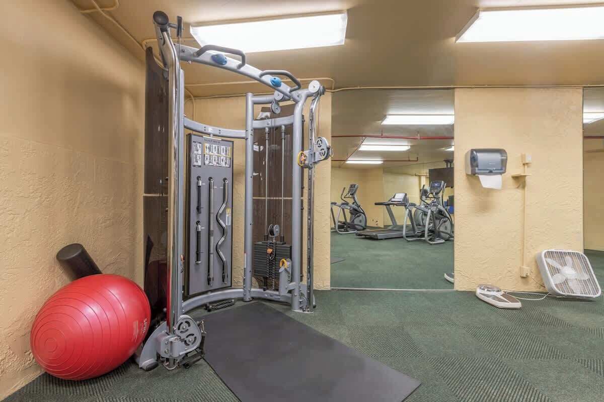 Une salle de sport équipée de matériel d’exercice, avec un ballon rouge et un miroir qui reflète l’espace.