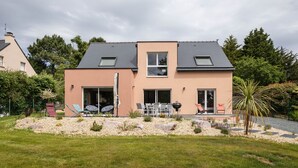 Ein modernes, zweistöckiges Haus mit einer Terrassenanlage, komplett mit Gartenmöbeln und Grill.