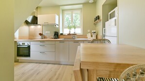 Une cuisine moderne dotée d’un four encastré, d’un évier et d’un coin repas avec une table et des chaises en bois.