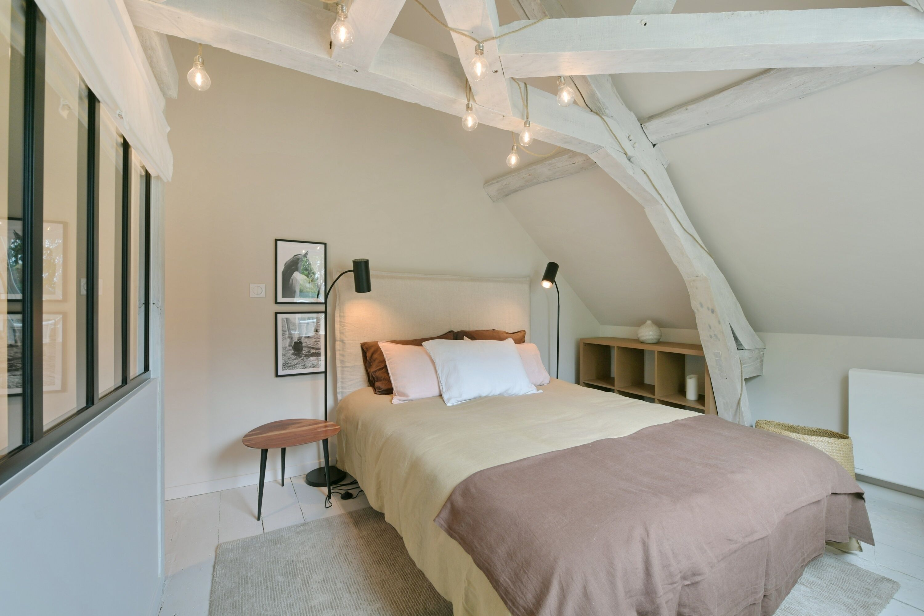 A bedroom with a bed, bedside tables, a nightstand, a lamp, and a window.