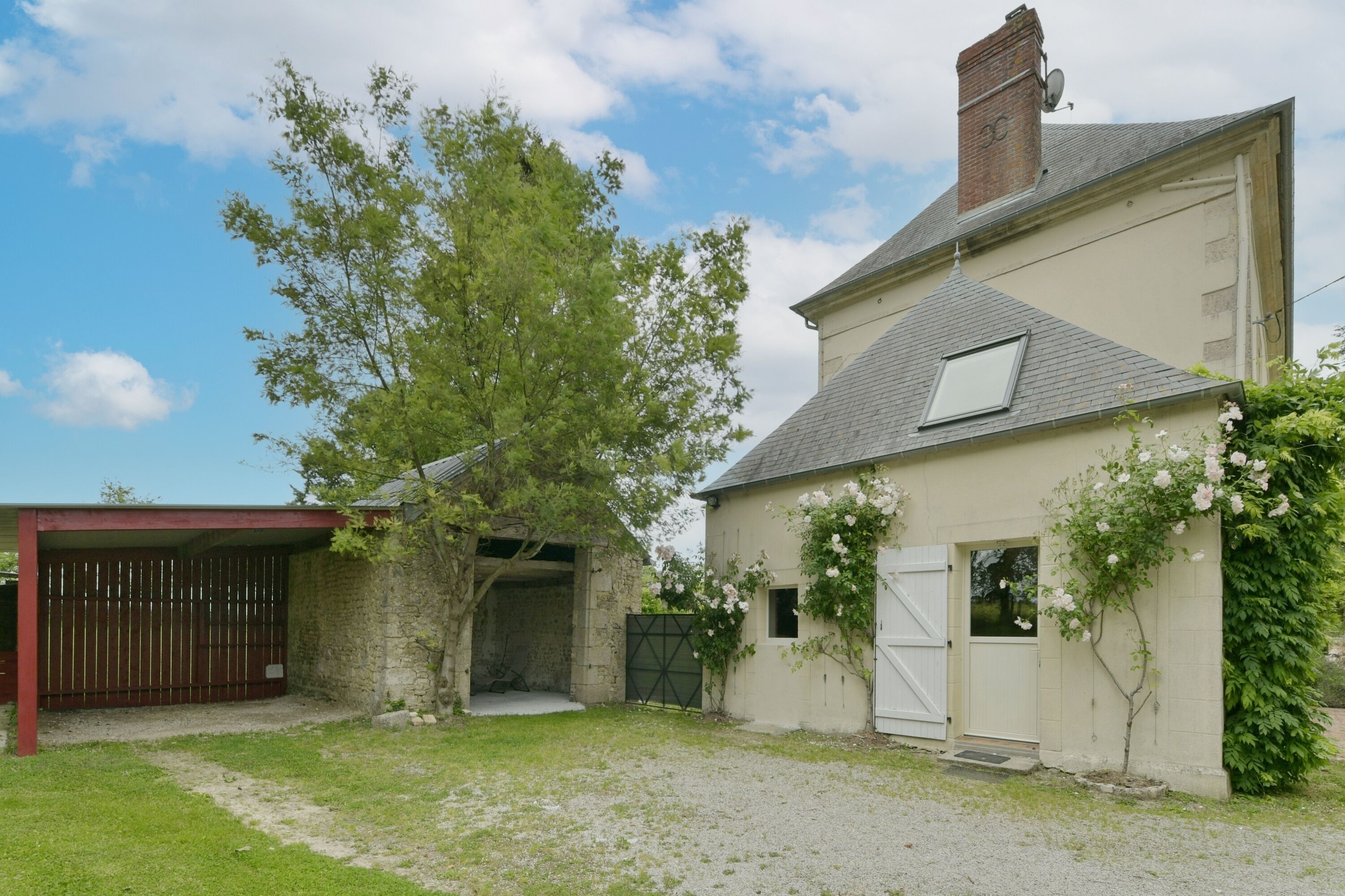 A two-story house with a garage, a covered patio, and a garden with flowering plants.