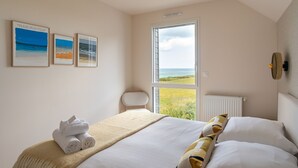 Ein Schlafzimmer mit einem Bett, Meerblick und drei gerahmten Bildern an der Wand.