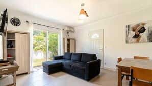 Een moderne woonkamer met een hoekbank, een eettafel met stoelen, een televisie en een klok aan de muur.