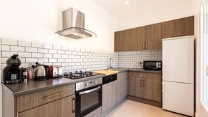 Een moderne keuken met een gasfornuis, oven, magnetron en een witte koelkast.