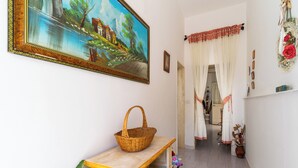 A hallway with a painting, a wicker basket, and a plant.