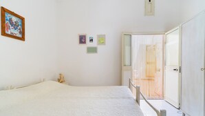 Une chambre à coucher avec un grand lit, une chaise en bois, une petite statue et une porte donnant sur un balcon.
