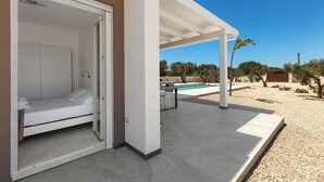 Un dormitorio moderno con una puerta corredera, una cama pequeña y un ventilador de techo blanco.