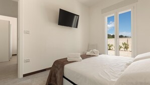 Un dormitorio con cama, televisor montado en la pared y vistas al exterior a través de un ventanal.