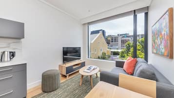 Una sala moderna con televisor, sofá y mesa de comedor.