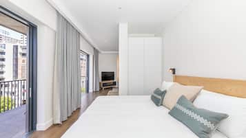 Una habitación de hotel moderna con una cama grande, un televisor y un balcón con cortinas.