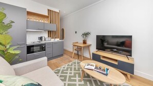 Un soggiorno moderno con cucina, zona pranzo e TV.