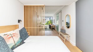 Una camera da letto moderna con un grande letto, un divisorio in legno, una scrivania e vista sull'esterno.