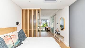 A modern bedroom with a large bed, a wooden partition, a desk, and a view of the outside.