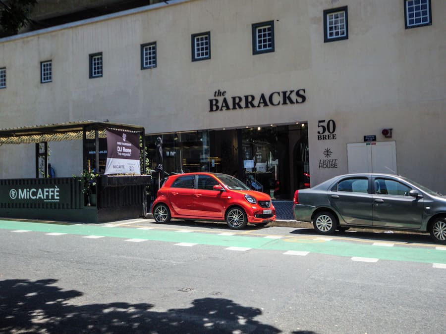 Um edifício com fachada comercial identificado como 'The Barracks' e um anúncio para '50 BREE Light House'.