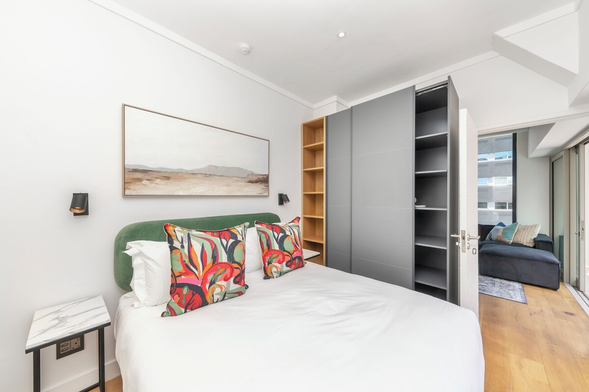 Un dormitorio moderno con cama, un cuadro, un armario y vistas al exterior.