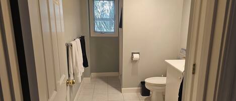 Un baño pequeño con inodoro, ventana y toallero.